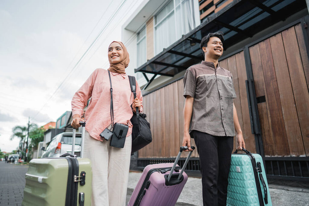 asian muslim couple with suitcase prepare to go. concept of man and woman travelling for eid mubarak celebration - Photo, Image