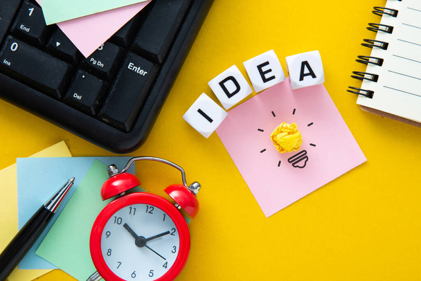 The words idea on yellow background  with a light bulb. Business action plan or creative idea planning strategy concept. - 写真・画像