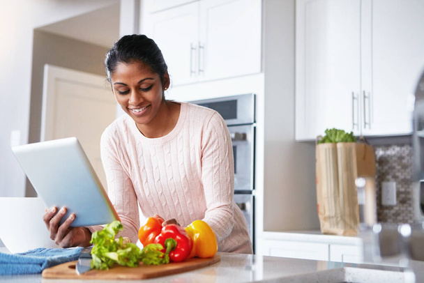 So many cooking apps with just one tap. a young woman using a digital tablet while preparing a healthy meal at home - Foto, immagini