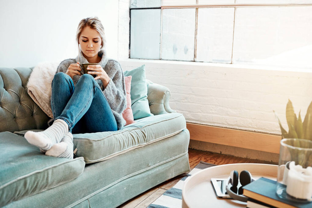 Иногда твоя компания лучшая компания. молодая женщина отдыхает на диване дома с теплым напитком - Фото, изображение