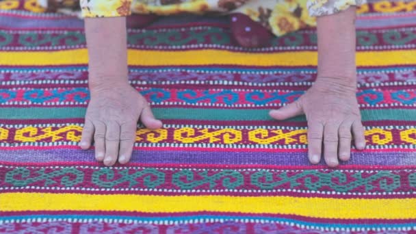 Die Hände einer alten Frau streicheln einen handgefertigten Teppich mit antiken Technologien nach asiatischem Muster - Filmmaterial, Video