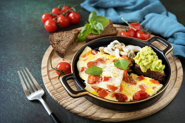 Omelet of omelet met paprika 's en tomaten, toast brood met avocado en gezouten zeevruchten. Gezonde Keto dieet met weinig koolhydraten ontbijt. Kopieerruimte. - Foto, afbeelding