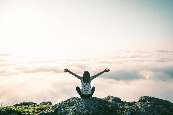 Backside strong woman figure sitting spread hands arms up dreamy above the clouds.Concept of victory and achievements, freedom, joy and solitude healthy outdoors. Spring welcome - Photo, image