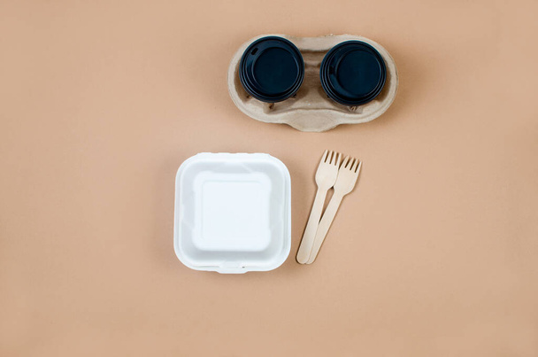 Top view on  disposable paper cups, launch box, wooden cutlery on beige. Kraft paper food packaging and wooden cutlery. Street food paper packaging from natural material. rejection of plastic. - Фото, изображение