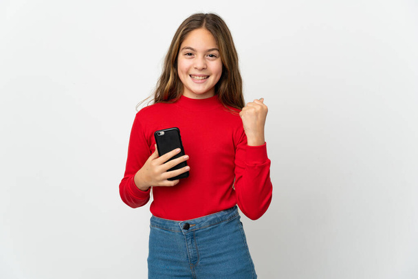 Bambina su sfondo bianco isolato con telefono in posizione di vittoria - Foto, immagini