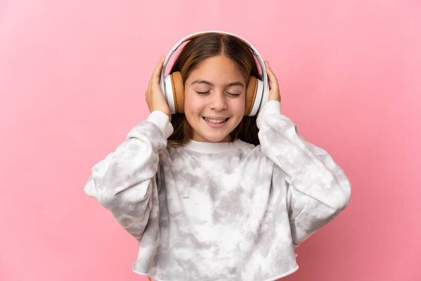 Ребенок на розовом фоне слушает музыку - Фото, изображение