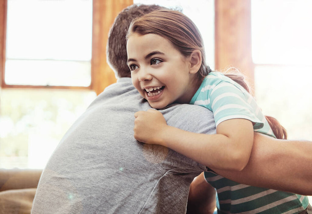 Αγκαλιές γεμάτες αγάπη. Ένα κοριτσάκι αγκαλιάζει τον πατέρα της στο σπίτι. - Φωτογραφία, εικόνα