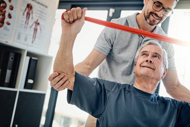 Stretching his limits a little every day. a friendly physiotherapist helping his mature patient to stretch at a rehabilitation center - Fotografie, Obrázek