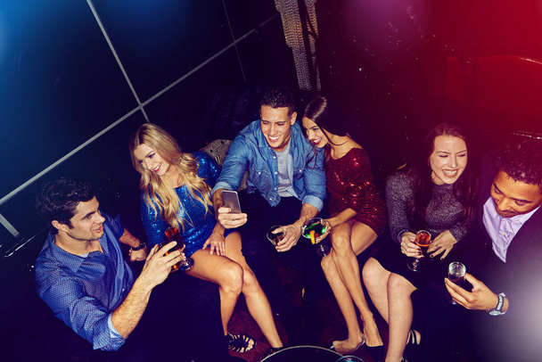 A festejar com as nossas pessoas favoritas. um grupo de amigos tirando selfies em um telefone celular em uma festa - Foto, Imagem