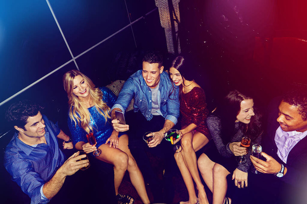 O seu local de noite favorito para soltar. um grupo de amigos tirando selfies em um telefone celular em uma festa - Foto, Imagem