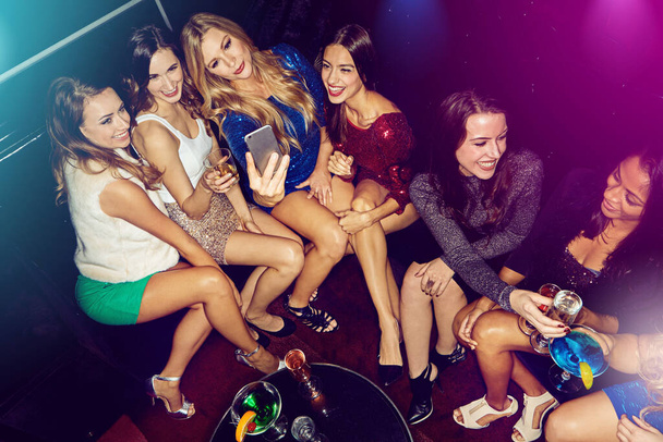 Their party selfies are on point. a group of friends taking selfies on a mobile phone at a nightclub - Foto, imagen