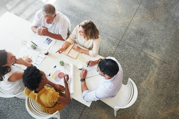 Lets add that idea to the agenda. High angle shot of a team of businesspeople having a meeting around a table in their office - Foto, imagen