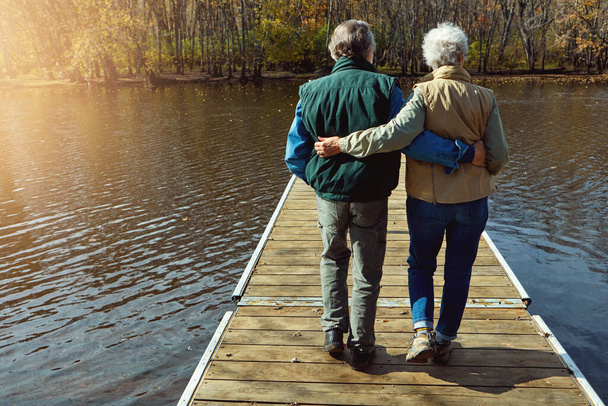 Nada más relajante que un día en la naturaleza. Vista trasera de una pareja de ancianos de pie en un muelle junto a un lago - Foto, Imagen