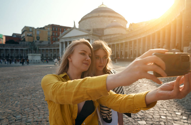 Two female tourists making selfie on Piazza del Plebiscito. - 写真・画像