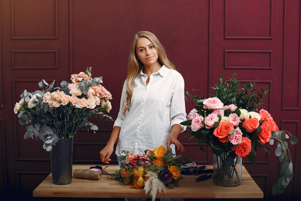 Florisr with flowers. Women makes a bouquete. Cute girl working - 写真・画像
