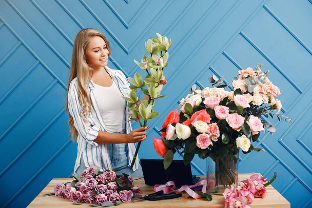 Florisr with flowers. Women makes a bouquete. Cute girl working - 写真・画像