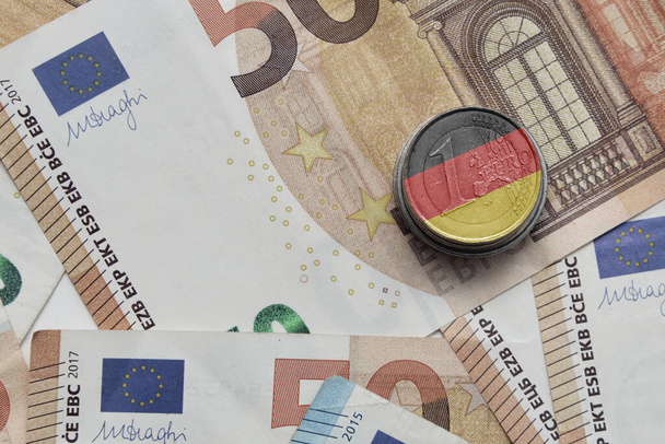 euromunt met nationale vlag van Duitsland op de euro geld bankbiljetten achtergrond - Foto, afbeelding
