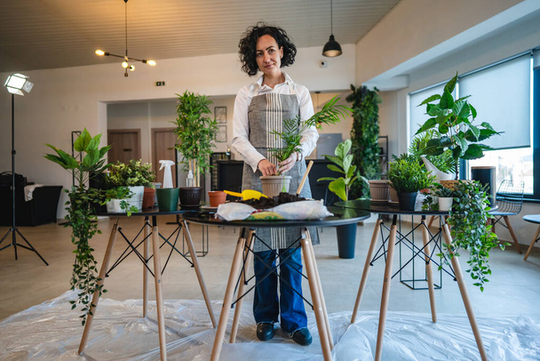 Egy érett nő kaukázusi női kertész vagy virágárus vigyázni és termeszteni háztartási virágok növények otthon kertészeti koncepció másolja tér transzplantáció pot - Fotó, kép
