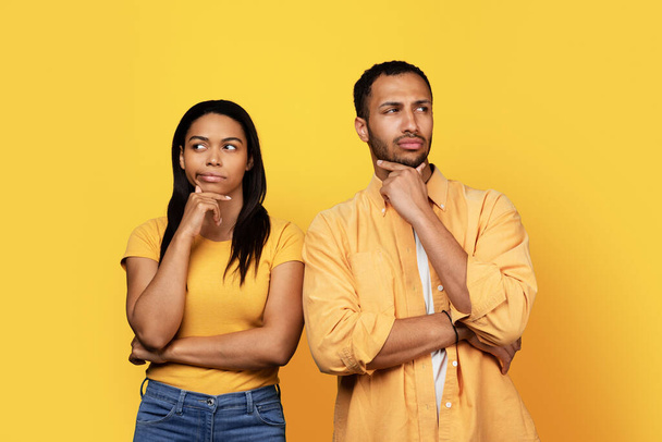 Binlerce yıllık Afro-Amerikan erkek arkadaşı ve kadın, sarı stüdyo arka planında izole edilmiş, boş bir alana bakıyorlar. Seç, reklam ve teklif, satış ve insanların duyguları - Fotoğraf, Görsel