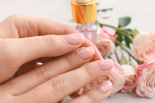 Vrouw aanbrengen van olie op nagelriemen op lichte achtergrond, close-up - Foto, afbeelding