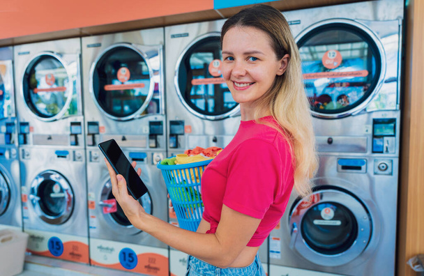 Young woman pays for laundry service using phone and banking application. - Φωτογραφία, εικόνα