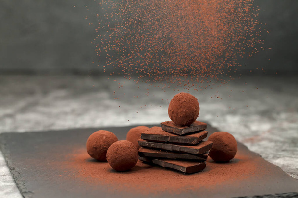 Chocolate candy. Round sweets. Cocoa powder. Closeup horizontal vew of homemade vegan paleo chocolate truffles on a gray background. Healthy eating concept - Zdjęcie, obraz
