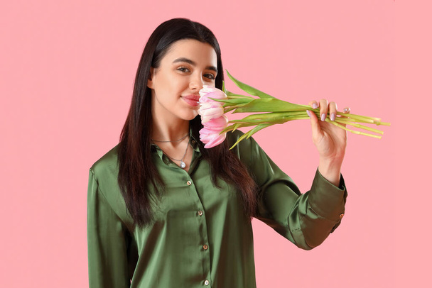 Beautiful happy young woman with bouquet of tulip flowers on pink background - Fotografie, Obrázek