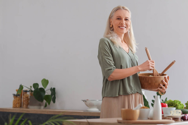 Felnőtt nő egy tál zöldségsalátával a konyhában - Fotó, kép