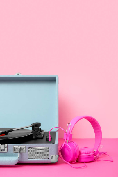 Плеер Record с виниловым диском и наушниками на столе у розовой стены - Фото, изображение