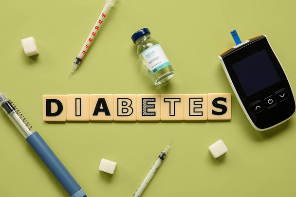 Word DIABETES with glucometer, insulin, lancet pen and sugar on green background. Diabetes concept - Photo, image