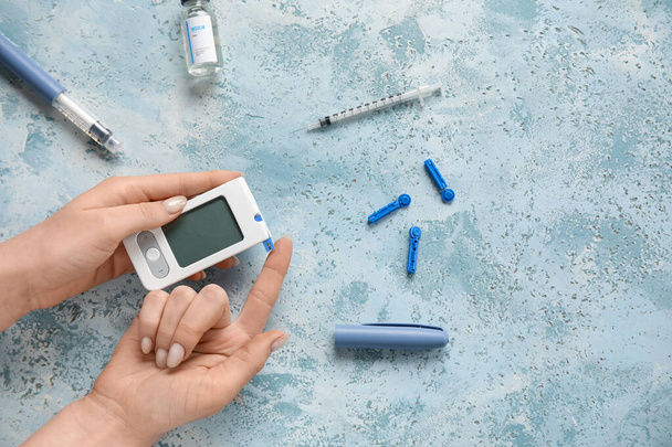 Diabetic woman using glucometer on grunge background - Photo, Image
