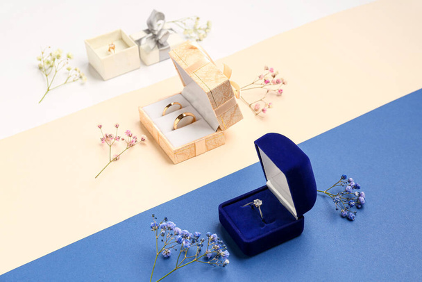 Flowers, boxes with wedding and engagement rings on color background - Φωτογραφία, εικόνα