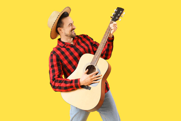 Bonito homem a tocar guitarra no fundo amarelo. Festa Junina (Festival de Junho) celebração - Foto, Imagem