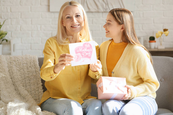 Young woman greeting her mother with card and gift at home - Photo, Image