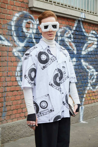 MILAN, ITALY - FEBRUARY 22, 2023: Man with white fur sunglasses and shirt with casette tape design before Fendi fashion show, Milan Fashion Week street style - Foto, immagini