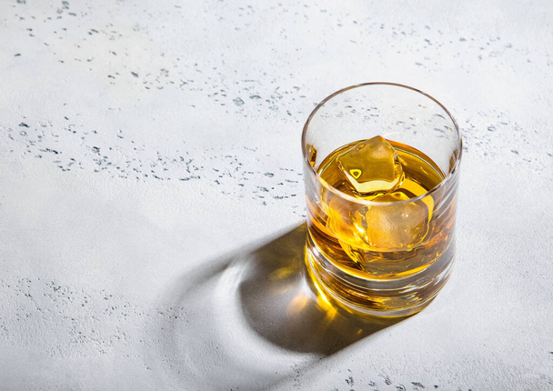 Glass of finest whiskey with ice cubes on light background.Macro - Zdjęcie, obraz