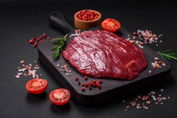 塩と新鮮な生牛肉,スパイスやハーブの暗い具体的な背景に - 写真・画像