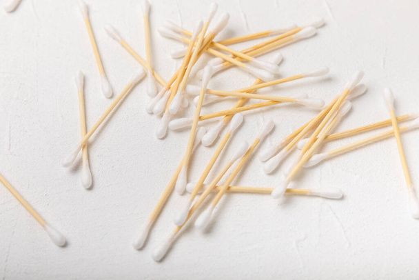 Cotton swabs on a white cement background. Bamboo cotton buds. Means for hygiene of ears. Eco-friendly materials.Hygienic cotton ear buds. - 写真・画像
