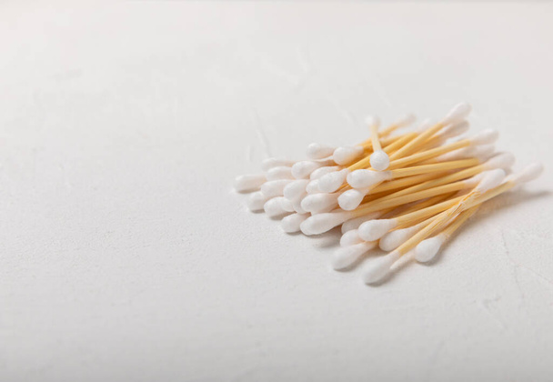 Cotton swabs on a white cement background. Bamboo cotton buds. Means for hygiene of ears. Eco-friendly materials.Hygienic cotton ear buds. - Photo, Image