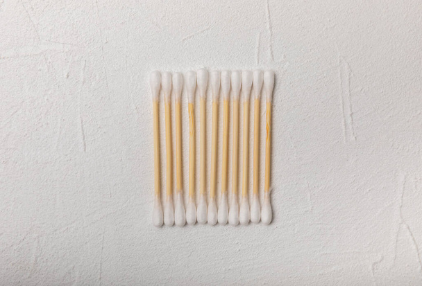 Cotton swabs on a white cement background. Bamboo cotton buds. Means for hygiene of ears. Eco-friendly materials.Hygienic cotton ear buds. - Photo, image