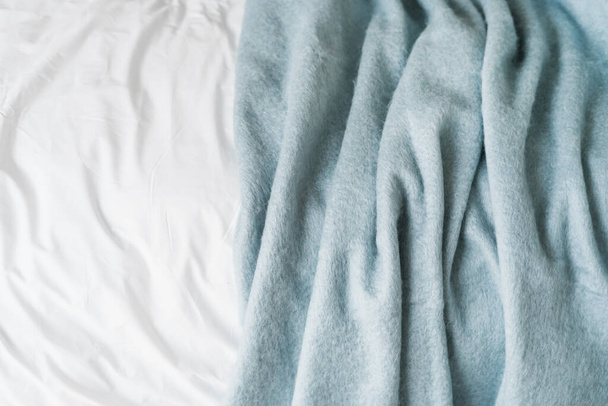 vista dall'alto di plaid di lana stropicciata su lenzuolo di cotone bianco in camera da letto, texture sfondo astratto, dettaglio all'interno - Foto, immagini