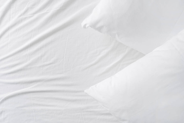 top view of soft pillows in cotton clean pillowcase on comfort mattress with bedclothes at hotel room, creased surface, background with copy space - 写真・画像