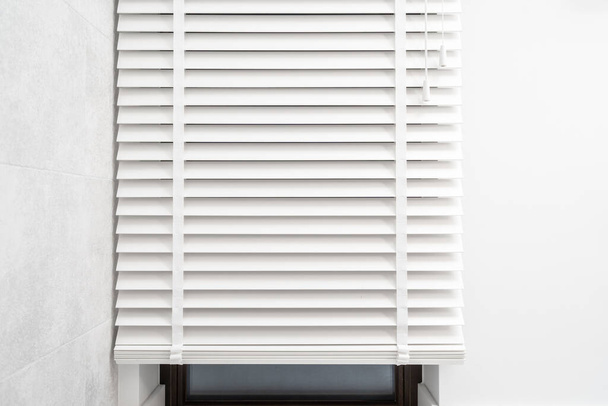 Horizontal jalousie in traditional venetian style made from natural material. Wooden horizontal slats on shutter in the room. Concept window blinds design for house, office and residential buildings - Photo, Image