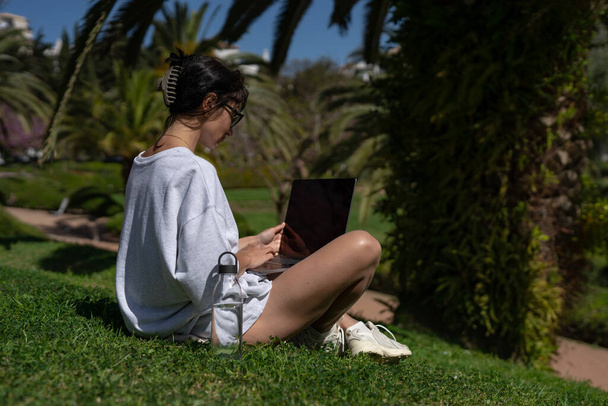 uma bela garota freelancer em óculos funciona em um laptop no  - Foto, Imagem