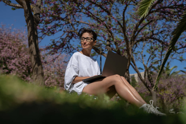 une belle fille pigiste dans des lunettes travaille à un ordinateur portable dans le  - Photo, image