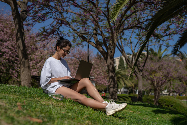 una hermosa chica freelancer en gafas trabaja en un ordenador portátil en el  - Foto, Imagen