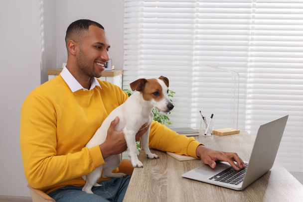 Jongeman met Jack Russell Terrier aan het werk op kantoor in het thuiskantoor - Foto, afbeelding