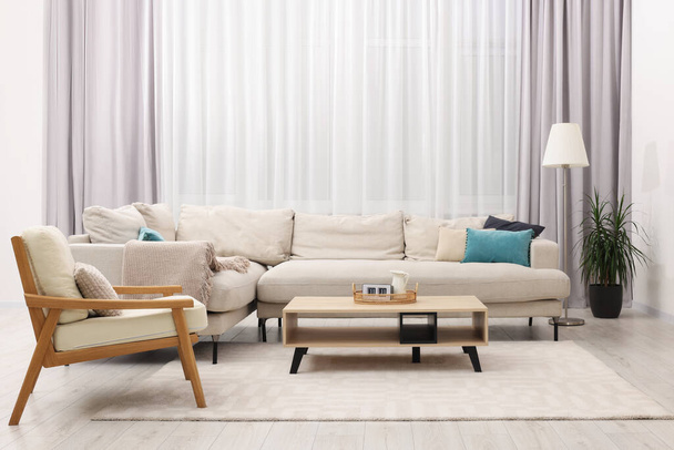 Stylish living room interior with cozy sofa, table and armchair - Fotó, kép