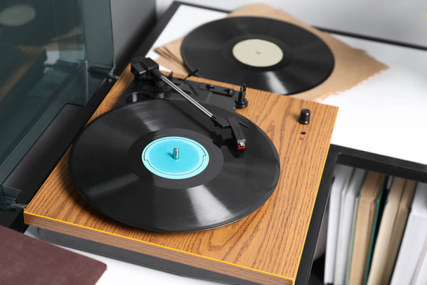 Stylish turntable with vinyl disc on table in room, closeup - Fotó, kép