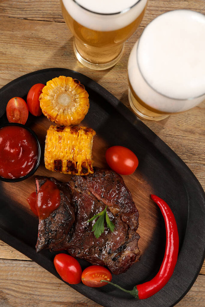 Glasses of beer, delicious fried steak and ingredients on wooden table, flat lay - Foto, immagini